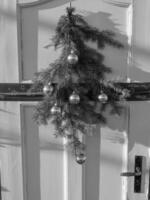 A black and white photo of a door with a christmas tree