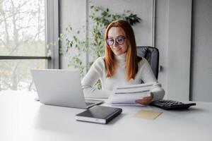 Businesswoman with invoices and documents calculating rates and KPIs. Cheerful business lady in an office working. Manager employee, account manager, accountant photo