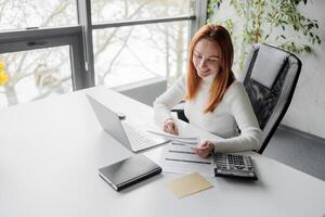 Happy, sophisticated, and elderly woman taking notes while working remotely from home. smiling middle-aged business woman watching webinar on computer. photo