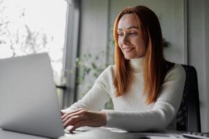 Happy, sophisticated, and elderly woman taking notes while working remotely from home. smiling middle-aged business woman watching webinar on computer. photo