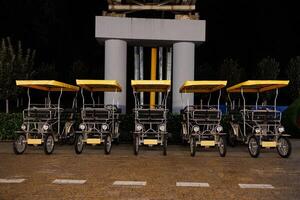 Pedal Power A Colorful Row of Yellow-Canopied Carts Await Adventure Under Sunny Skies. Discover the Joy of Exploration with These Vibrant, Playful Rides Ready for Fun. photo