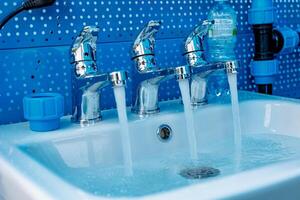 Triple Cascade A Dance of Water in a Gleaming Sink - Liquid Threads Weaving Through Chrome Faucets photo