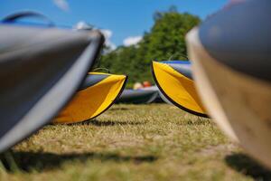 Colorful kayaks rest on a sunlit green lawn, inviting adventure and exploration while contrasting with the vibrant hues of nature. photo