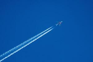 Sky Symphony An Airplane Dances Through the Azure Canvas, Leaving Behind a Whisper of Contrails. photo