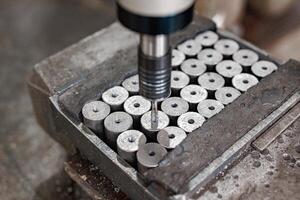 Precision in Motion A drill press expertly machining gleaming metal cylinders, creating perfectly crafted components with every calculated turn. photo