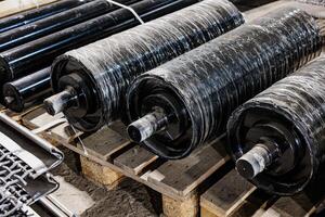 Heavy-duty industrial rollers stacked on a sturdy wooden pallet, showcasing gleaming metal surfaces that reflect a world of mechanical innovation and resilience photo