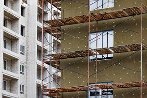 Steel beams rise against a twilight sky, wrapped in a web of scaffolding. The heartbeat of progress pulses through the skeletal structure, promising a future yet to unfold. photo