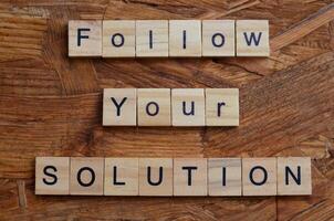 follow your solution text on wooden square background photo