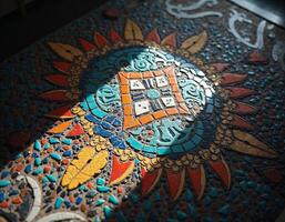 a colorful mosaic tile with a sun and a flower on it photo