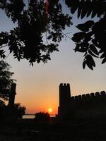 Majestic sunset view with medieval castle silhouette and trees photo