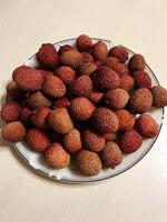 Fresh lychee fruits piled on a decorative plate for display photo