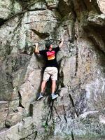 Man in casual attire rock climbing on natural cliff outdoors photo