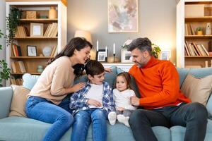 A family sitting on a couch in front of a bookcase photo