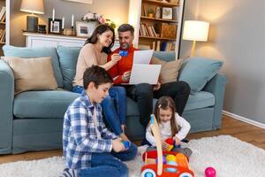 A family sitting on a couch with a laptop and toys photo