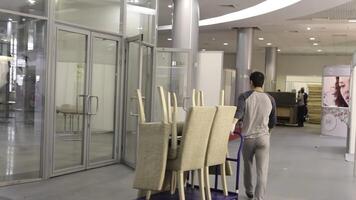 A man skillfully pushes a cart with chairs and a piano indoors photo