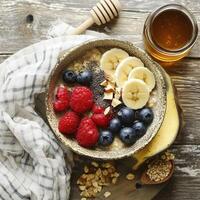 Oatmeal with banana, blueberries, raspberries and chia seeds on a wooden background photo