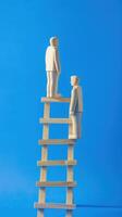 Businessman standing on ladder on blue background. Concept of career growth photo