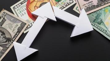 Business and finance concept. Paper arrows and money on black background. photo