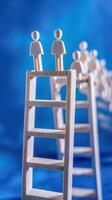 Businessman standing on ladder on blue background. Concept of career growth photo