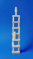 Businessman standing on ladder on blue background. Concept of career growth photo