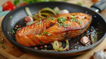 Fried salmon steak with cooked leek and garlic on frying pan on wooden table photo