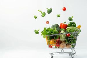 A long format copy space image featuring fresh vegetables falling into a shopping basket on a white background photo