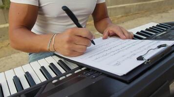 Man Writes Chords On Sheet Music And Study On Keyboard Instrument video