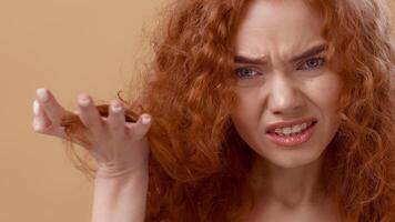 A woman with striking curly red hair displays a puzzled expression while gesturing with her hand, set against a neutral beige background. Her brow is furrowed, capturing curiosity. video