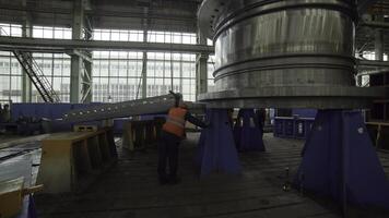 An Industrial Worker Actively Handling a Large Machinery Component Inside a Factory Environment. Stock Clip photo