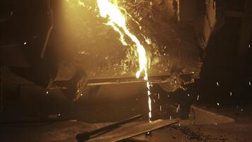 Molten metal is being poured out, producing bright sparks within a vibrant foundry environment. Stock Clip photo