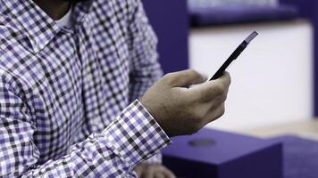 A man is utilizing his smartphone in a contemporary environment filled with various modern elements. Media photo