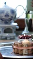 Female hand rotate metal tray with burning candle on kitchen table and show handcrafted candle holder made from empty jam jar with used wine corks. Recycled home decor, hobby. Vertical format video