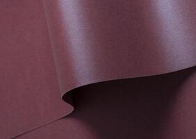 Burgundy metallic paper background with a shimmering, sleek surface and soft folds. Featuring a rich photo