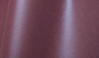 Metallic burgundy paper background with a shimmering, glossy surface and soft folds. Featuring a photo