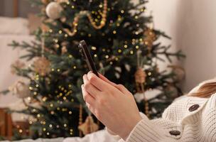 Lodz Poland July 20 2024, hands holding and using mobile phone, iphone smartphone on Christmas photo