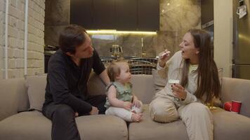 Young mother is playing with her child while feeding him spoonful of yogurt. child, enjoying game, is eating food with pleasure. video