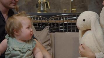 A mother plays with her child, using a toy rabbit. She talks to her daughter, kissing her gently on the cheek. video