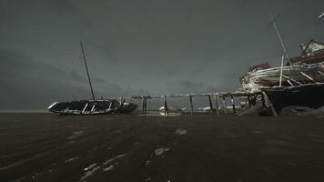 Abandoned boat on a broken pier under a dark cloudy sky at dusk video