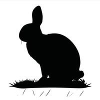 A black and white silhouette of a rabbit sitting on grass vector
