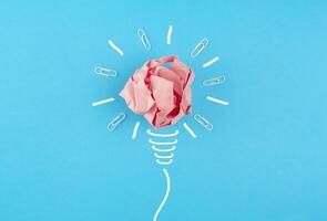 Crumpled pink paper lamp on a blue background. New idea, innovation and concept of solutions. Business idea. Business concept. Recovery, business revitalization. photo