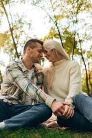 Couple in love hugging together sitting on blanket on green grass in park outdoors having picnic photo