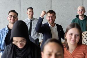A diverse team of business professionals ecstatically celebrating their success in a modern office, expressing triumph and unity after achieving their goals photo