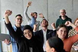 A diverse team of business professionals ecstatically celebrating their success in a modern office, expressing triumph and unity after achieving their goals photo
