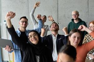A diverse team of business professionals ecstatically celebrating their success in a modern office, expressing triumph and unity after achieving their goals photo