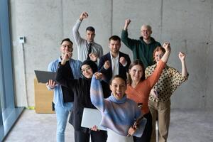 A diverse team of business professionals ecstatically celebrating their success in a modern office, expressing triumph and unity after achieving their goals photo