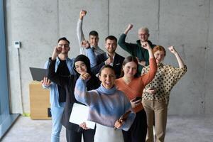 A diverse team of business professionals ecstatically celebrating their success in a modern office, expressing triumph and unity after achieving their goals photo