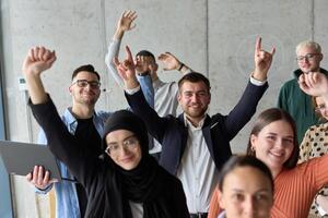 A diverse team of business professionals ecstatically celebrating their success in a modern office, expressing triumph and unity after achieving their goals photo