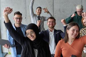 A diverse team of business professionals ecstatically celebrating their success in a modern office, expressing triumph and unity after achieving their goals photo