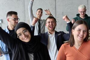 A diverse team of business professionals ecstatically celebrating their success in a modern office, expressing triumph and unity after achieving their goals photo