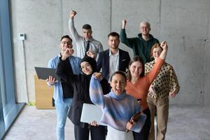 A diverse team of business professionals ecstatically celebrating their success in a modern office, expressing triumph and unity after achieving their goals photo